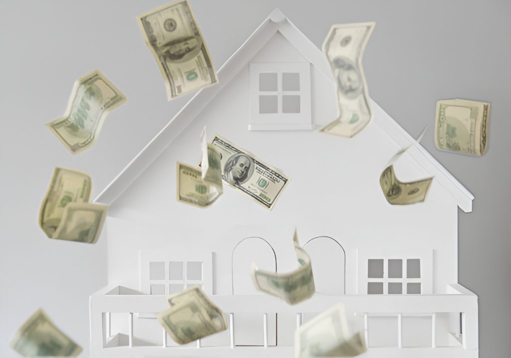 dollar bills falling over against a white miniature house